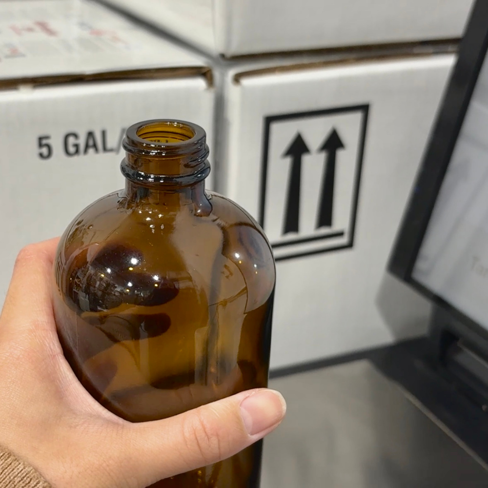 Person places amber glass bottle on scale to weigh before refilling it with soap.